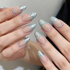 Close-up of French press-on nails with silver spiral pattern and blue rhinestone detail