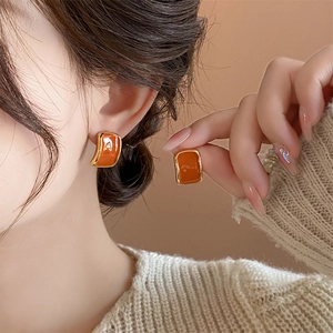 Chic gold-plated square stud earrings with orange enamel inlay worn by a model