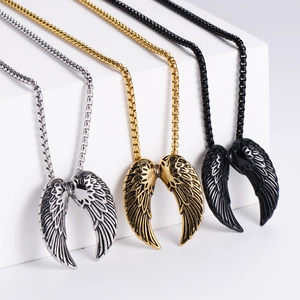 Three angel wing necklaces in gold, silver, and black finish on geometric stands