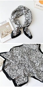 Detail of elegant black and white silk scarf with large rose floral prints and black borders