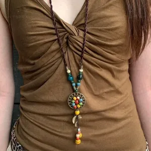 Ethno-Böhmische lange Kette mit bunten Perlen und Bronze-Blumenanhänger am Model
