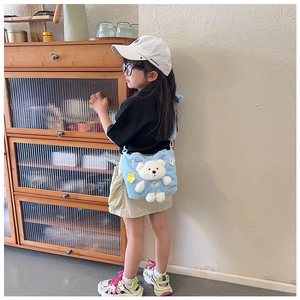 Girl's light blue plush crossbody bag with cute 3D bear and flower details worn by model