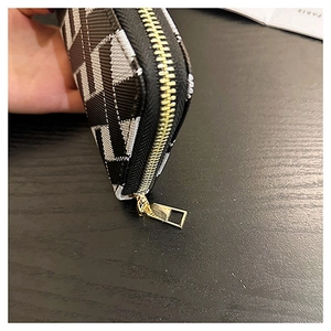 Close-up of geometric cross pattern on wallet with premium gold zipper detail