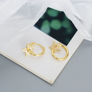 Macro detail of golden star-shaped charm earrings encrusted with sparkling zircon stones