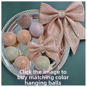 Rose gold glitter bow and matching shiny ornaments arranged on a silver tray for Christmas