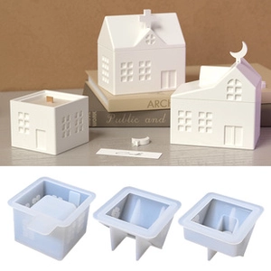 Silicone house molds and finished wax candles on a warm wooden background display