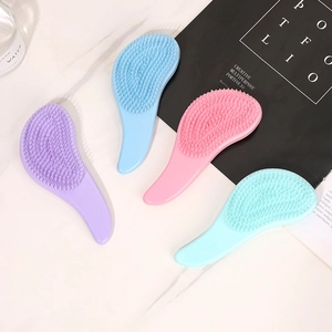 Set of four ergonomic macaron-colored detangling hairbrushes on marble surface