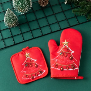 Close-up of red Merry Christmas oven mitt and pot holder set on festive table
