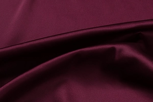 Close-up of premium burgundy satin fabric showing elegant silk luster and smooth drape