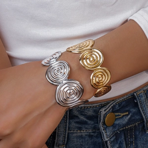 Detail view of bold spiral geometric open bracelets in polished gold and silver finishes