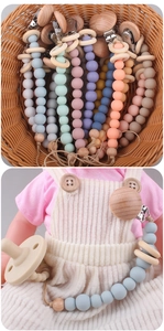Detailed view of colorful silicone and wood baby pacifier clips attached to doll clothing