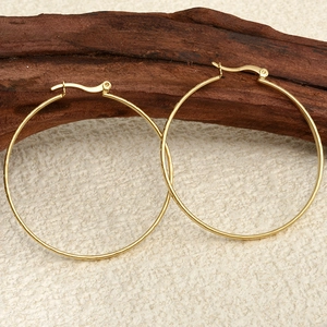 Detail of minimalist 304 stainless steel large gold hoop earrings on wooden background