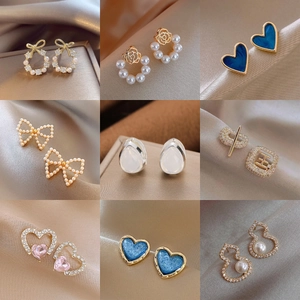 Elegant pearl and diamond geometric earrings collection on soft silk background