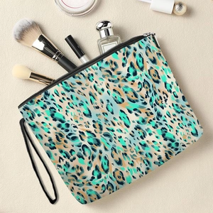 Teal leopard print makeup bag with wristlet strap and golden cosmetics on light background