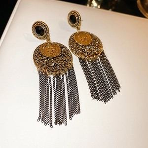 Détail macro de boucles d'oreilles franges dorées vintage avec pièce française et gemme