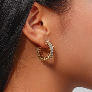 Détail macro de boucles d'oreilles créoles C en plaqué or 18K avec zircons carrés