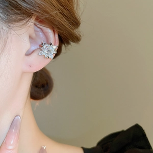 Detail of silver star ear cuff with cubic zirconia on model's ear, sleek stylish look
