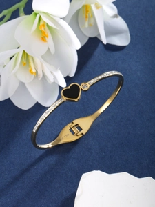 Detail of gold-plated heart bracelet with black enamel finish and sparkling white zircons