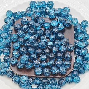 Macro detail of round blue crackle glass beads with white patterns on a wood base