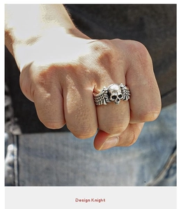 Detailed close-up of a vintage silver punk skull ring with wings on a male hand