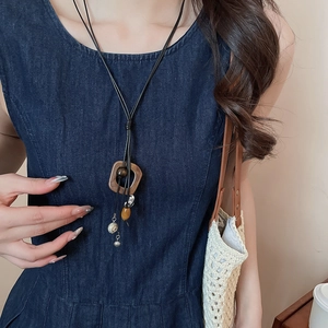 Close-up of a long ethnic style necklace with amber beads and brown geometric pendants