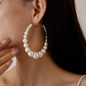 Elegant large hoop earrings with gradient pearls and gold finish on a female model