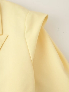 Macro d'un blazer jaune montrant la texture du sergé et les coutures de l'épaule