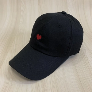 Detailed close-up of the red heart embroidery on this black cotton baseball cap