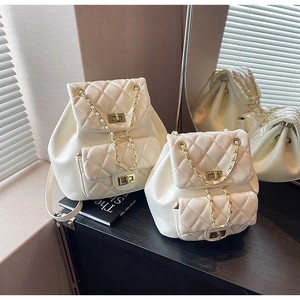 Detailed view of quilted cream backpacks with gold chain straps and turn-lock closure