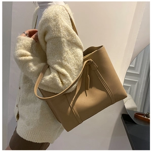 Brown soft leather tote bag with long shoulder straps and decorative hanging tag detail