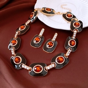 Détail d'un ensemble de bijoux vintage doré avec émail noir et pierres orange