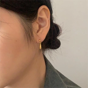 Primo piano di una modella con orecchini a lobo dorati a goccia dal design minimalista