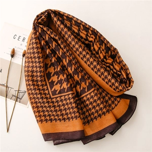 Close-up of orange houndstooth scarf with fine knit texture and neat edge stitching