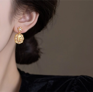Macro shot of vintage gold-plated oval relief earrings with white pearls and crystals
