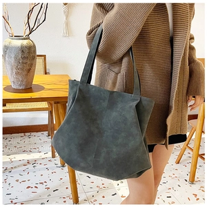 Minimalist large tote bag in dark gray matte leather worn over the shoulder by a model