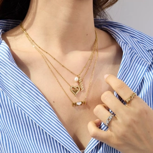Detailed view of layered gold MAMA necklaces with pearls and matching letter rings