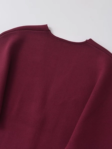 Macro detail of the back neckline and fine stitching on a deep burgundy knit cardigan