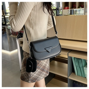 Détail du sac à bandoulière en cuir grainé noir avec triangle en métal et pochette ronde