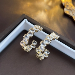 Macro shot of gold C-shaped earrings with clear crystals in a luxury jewelry gift box