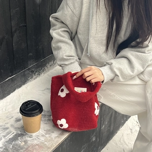 Detail of dark red felt handbag with white 3D floral accents and premium stitched label