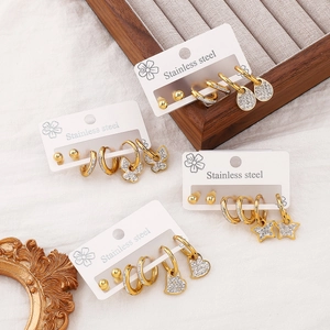 Golden stainless steel stud earrings set with crystal charms on a decorative tray