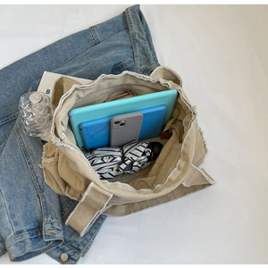 Detailed interior view of beige canvas tote bag with raw edges showing large capacity