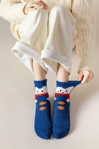 Gros plan de chaussettes en molleton corail à motif pingouin bleu portées aux pieds