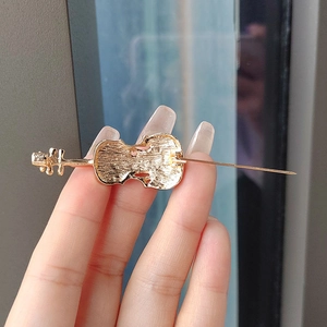 Back view of elegant gold violin brooch with textured surface and secure pin clasp