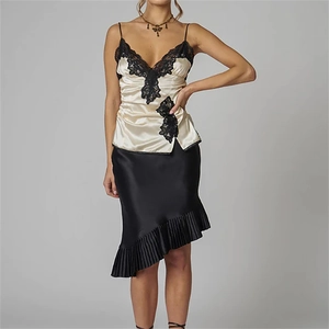 Detail of black pleated asymmetric skirt with elegant lace trim and silk texture finish