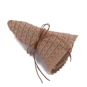 Close-up of brown lace sun hat with hollow floral texture and dark leather cord detail