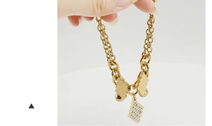Dettaglio bracciale in acciaio inossidabile dorato con pendente geometrico e tre file di strass