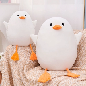 Detail of two white plush ducks in large and small sizes on a soft beige blanket