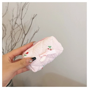 Detailed shot of a pink quilted floral cotton pouch with cherry embroidery and pink ribbon bow