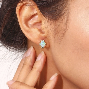 Detail of 18K gold petal opal earring with diamond halo on model's ear